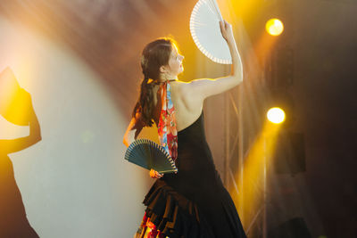 Young woman holding illuminated lighting equipment at night