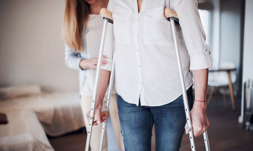 Daughter helping her mother to walk with crutches