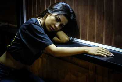 Depressed young woman leaning on shelf by wall