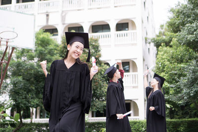 Cheerful student with clenched fist wearing graduation gown