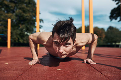 Shirtless man exercising on floor outdoors