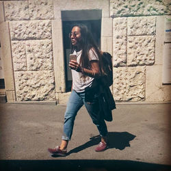 Portrait of smiling young woman standing against wall