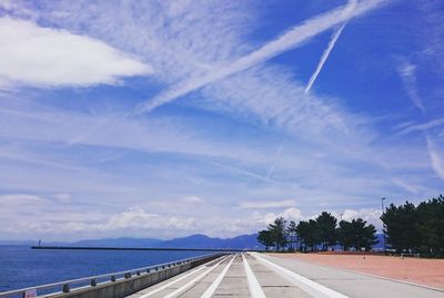 Empty walkway by sea against sky