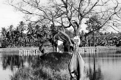 Woman standing by lake against trees