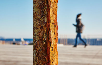 Woman walking at pier by sea against clear sky