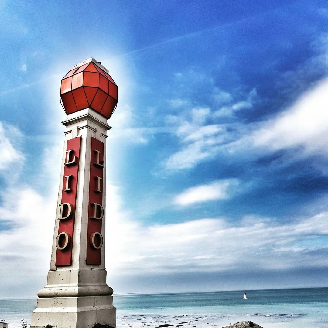 LOW ANGLE VIEW OF LIGHTHOUSE ON SEA AGAINST CLOUDY SKY