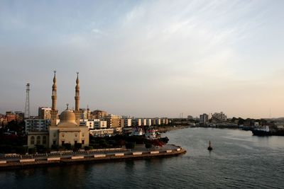 High angle view of buildings by river in city against sky