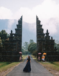 Woman walking on road against mountains