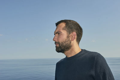 Portrait of young man looking at sea against sky