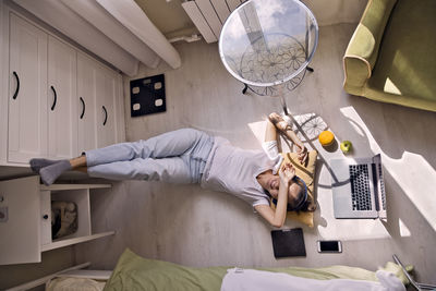 Young woman lying at the window at home with laptop