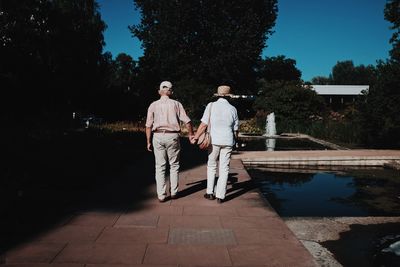 Men standing by swimming pool against trees