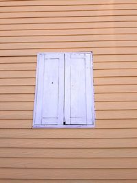 Close-up of closed window on wooden wall