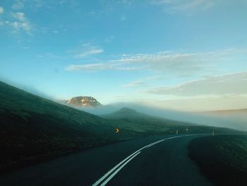 Road leading towards mountains against sky