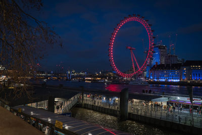 Illuminated ferris wheel in city at night