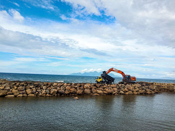 Man standing on rock by sea against sky