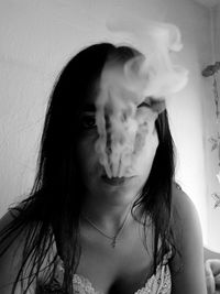 Portrait of young woman smoking against wall