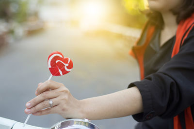 Close-up of hand holding heart shape lollipop