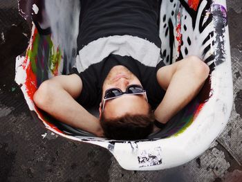 High angle view of young man resting in broken bathtub