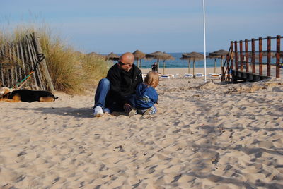 Father and daughter with dog at beach