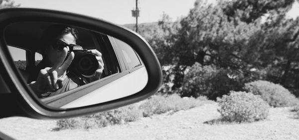 Reflection of man on side-view mirror