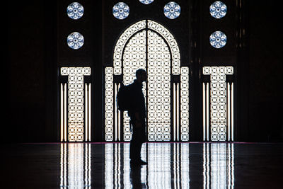 Silhouette of woman standing against door of building