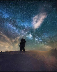 Rear view of man standing on field against sky at night