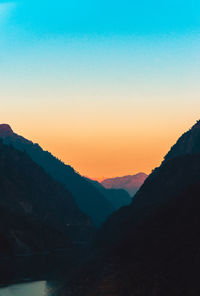 Scenic view of silhouette layered mountains against sky during sunset