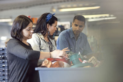 Volunteers discussing while looking at objects in crate at workshop