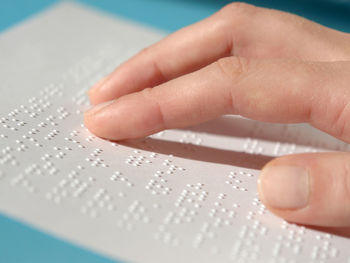 Cropped hand of blind woman reading braille