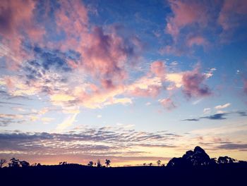 Scenic view of silhouette field against sky at sunset