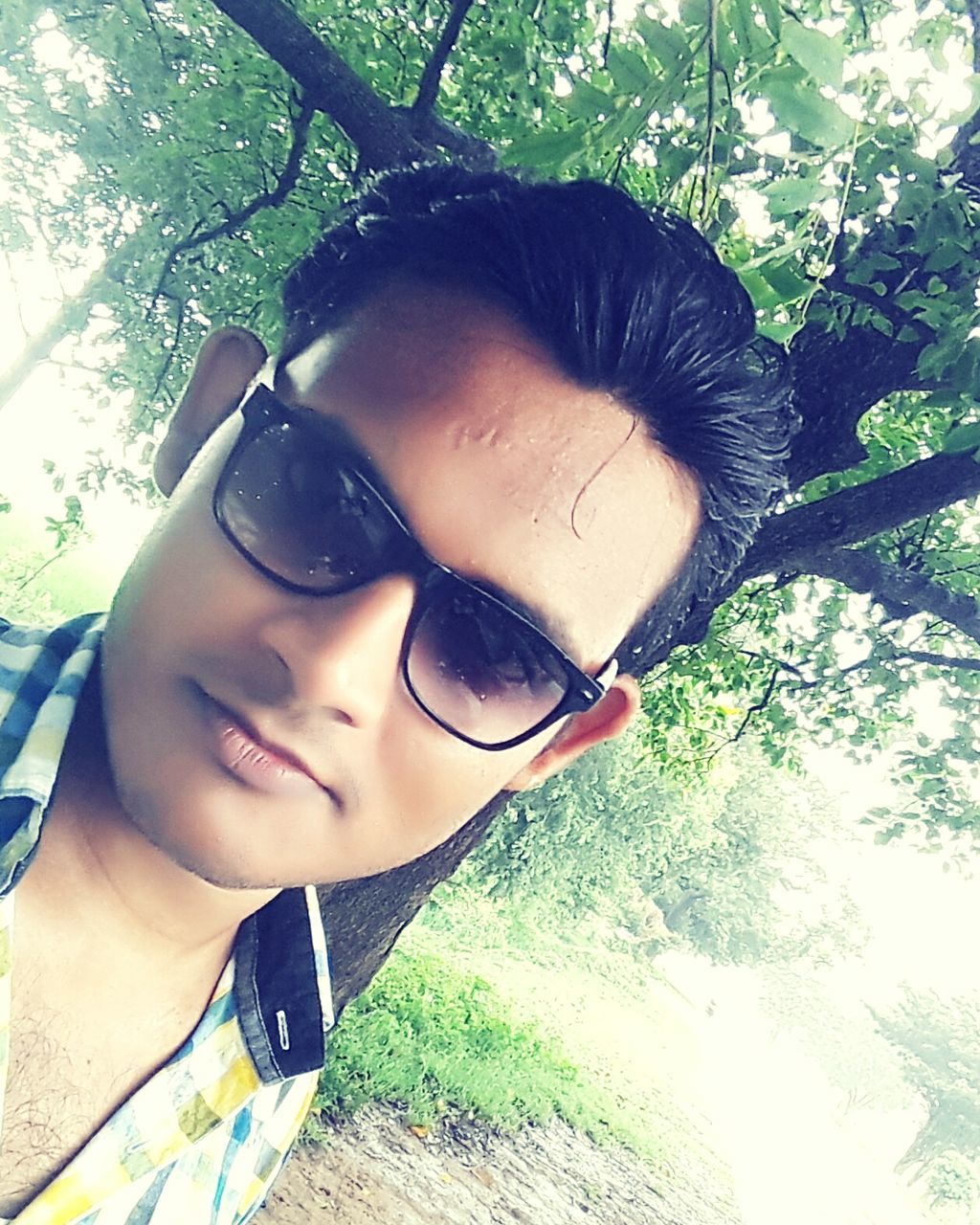 YOUNG MAN LOOKING AWAY WHILE STANDING IN PARK