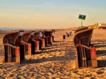 Hooded chairs on beach against sky