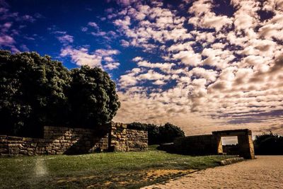 Built structure on landscape against cloudy sky