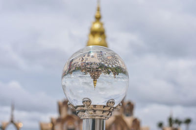 Close-up of glass of building against cloudy sky