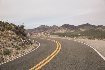 Road by mountains against sky