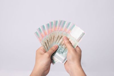 Close-up of hand holding umbrella against white background