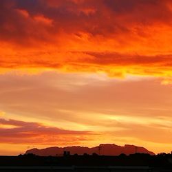 Silhouette landscape against dramatic sky during sunset