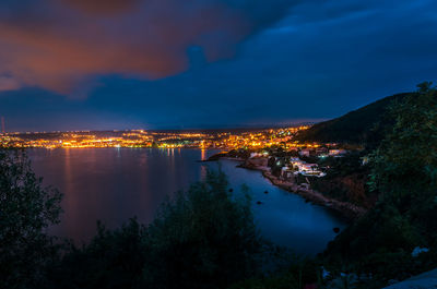 Illuminated cityscape of chenoua vilalge  by sea against sky at night