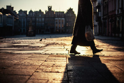 Low section of woman walking on street in city