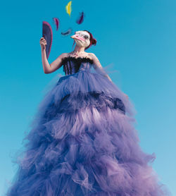 Low angle view of woman standing against blue sky