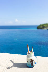 High angle view of drink on table at beach against blue sky