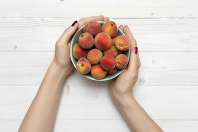 High angle view of hand holding apple on table