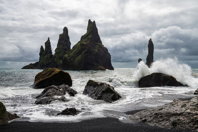 Rocks on shore by sea against sky