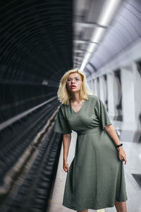 Portrait of beautiful woman standing on railroad track