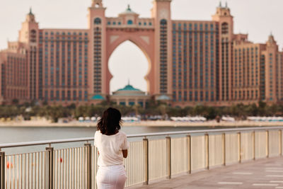 Rear view of woman standing by railing in city