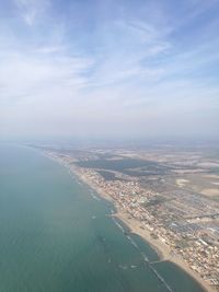 Aerial view of city by sea against sky