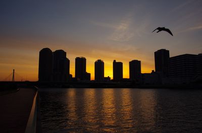 Silhouette of skyscrapers against sky during sunset