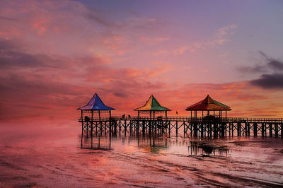 Lifeguard hut on beach against sky during sunset