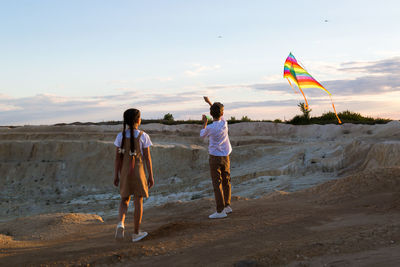 Rear view of woman walking on beach against sky