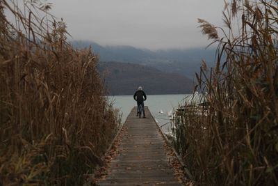 Rear view of man walking on boardwalk